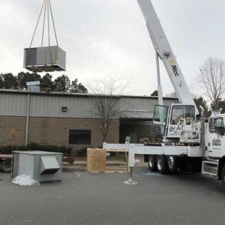 Crane lowering an air conditioning unit onto a commercial building
